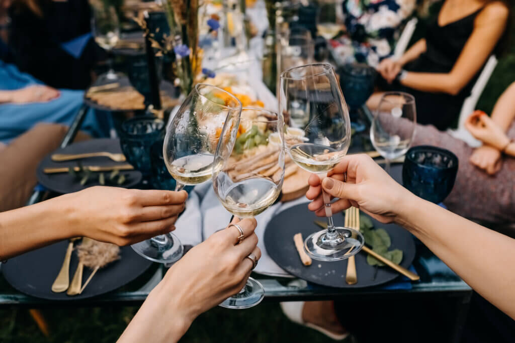 Women raising wedding wine glasses of white wine